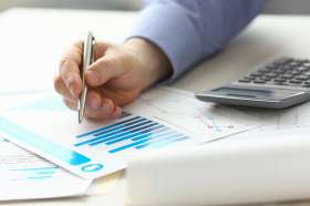 Foto: Diagramme, Taschenrechner und Hand mit Stift